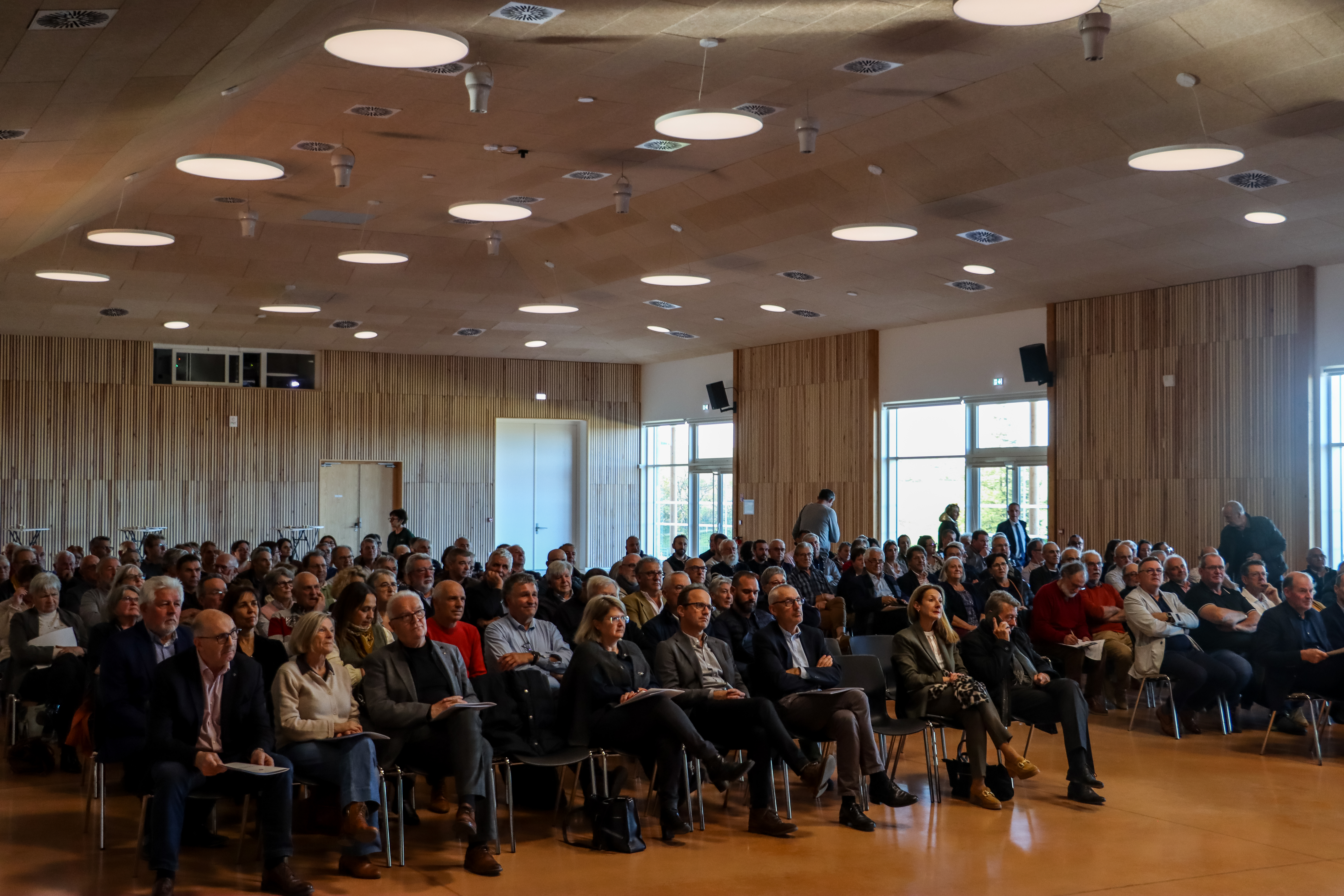 Photographie représentant l'assemblée des adhérents d'Aveyron Ingénierie, assis sur des chaises dans la nouvelle salle d'animation de Baraqueville.